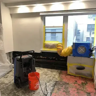 Dehumidifier and air mover drying out an emptied room after the wet flooring was pulled up