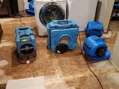 Air movers drying the floor beside a washer after an appliance leak