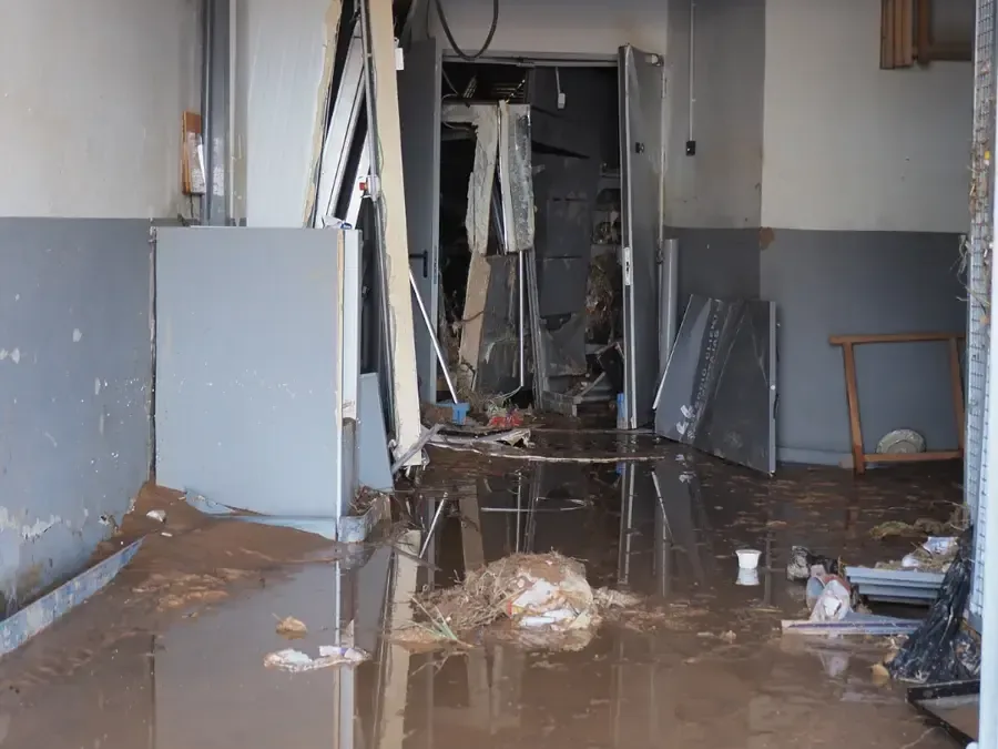 Gutted basement with muddy floodwater and debris across the floor
