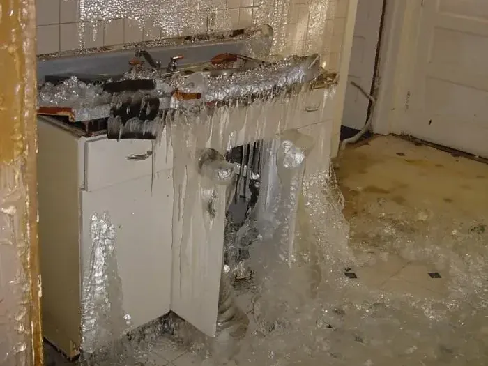 Ice coating a sink cabinet and floor after a supply pipe froze and split