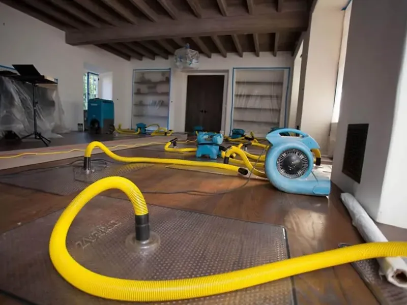 Technician running an extraction wand across a soaked floor